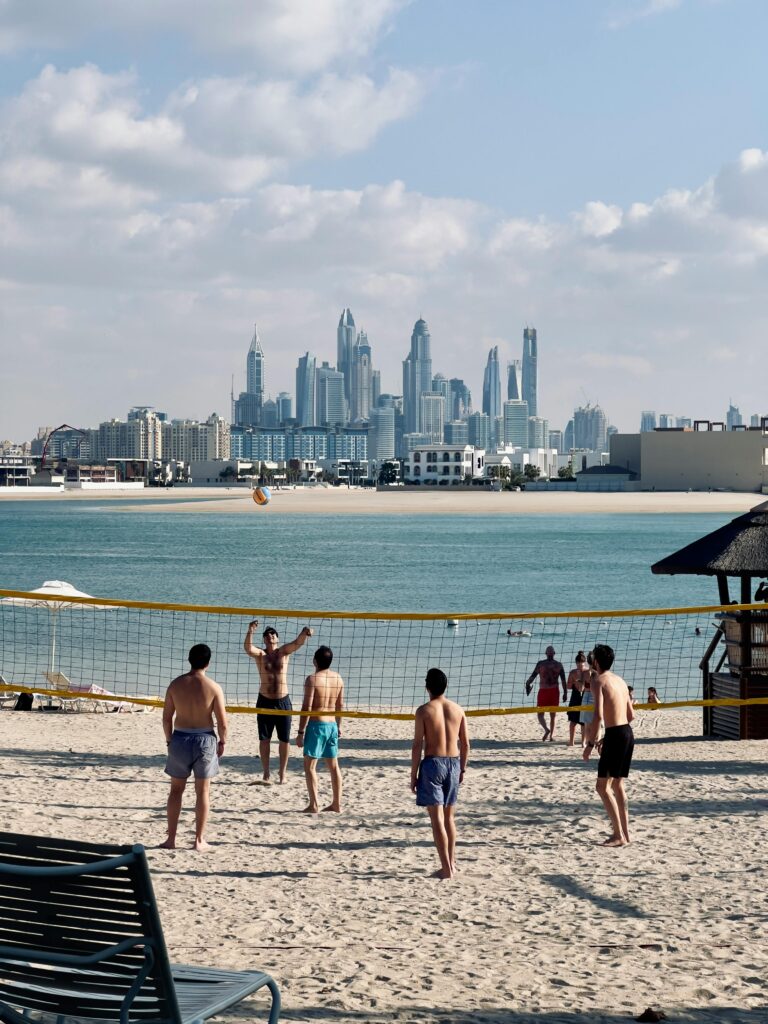 pexels photo 24862695 24862695 Men playing beach volleyball with the iconic Dubai skyline in the background.
